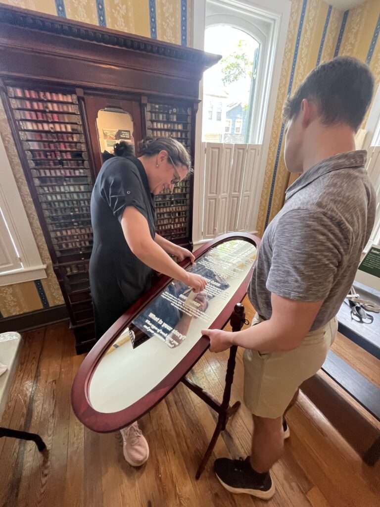 Sarah Coster of Sarah Consulting installing vinyl on a mirror for the Main Street at Work exhibit, Historical Society of Carroll County.